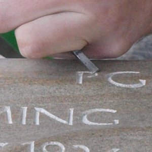 Steinmetz schlägt Buchstaben in einen Stein