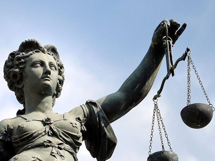 Justitia-Statue mit geschlossenen Augen und Waage in der Hand