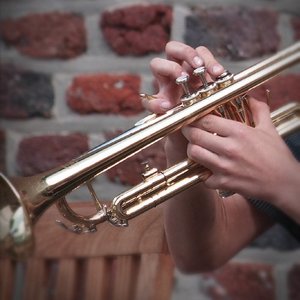 Mann spielt Trompete vor Ziegelmauer