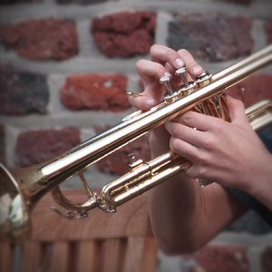Mann spielt Trompete vor Ziegelmauer
