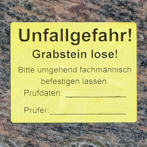 Aufkleber auf Grabmal mit Hinweis auf fehlende Standsicherheit
