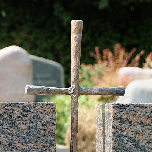 Grabmal aus Stein mit Kreuz aus Metall