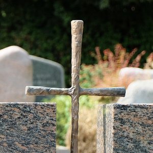 Grabmal aus Stein mit Kreuz aus Metall