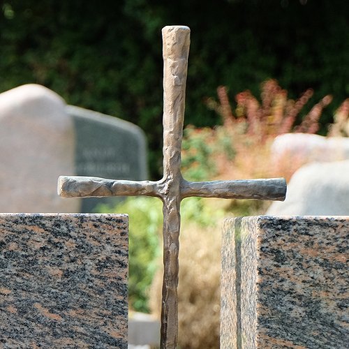 Grabmal aus Stein mit Kreuz aus Metall