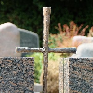 Grabmal aus Stein mit Kreuz aus Metall