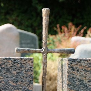 Grabmal aus Stein mit Kreuz aus Metall