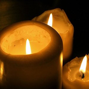 Drei brennende Kerzen in der Dunkelheit