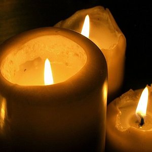 Drei brennende Kerzen in der Dunkelheit