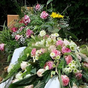 Blumenschmuck und Kränze auf der Grabstelle nach einer Bestattung