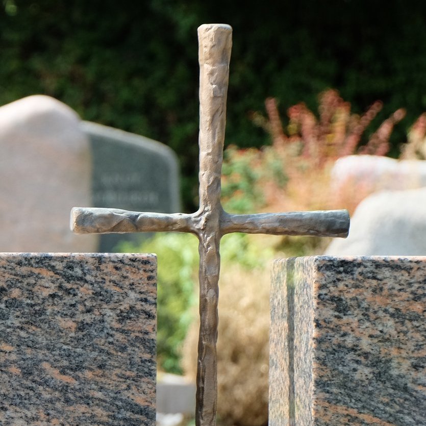 Kreuz aus Metall als Gestaltungselement eines Grabmals aus Stein
