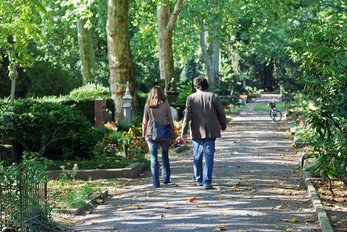 Zwei Personen spazieren über einen Friedhof